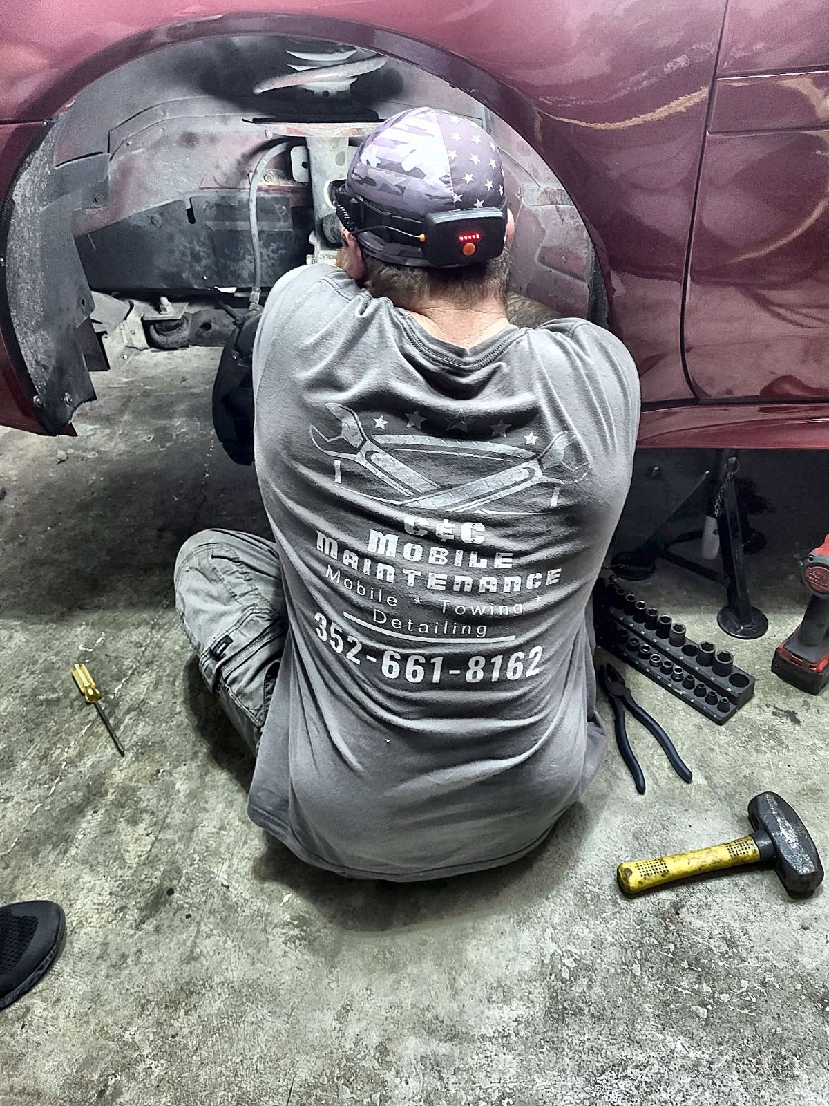C&C technician in a branded shirt working inside a wheel well
